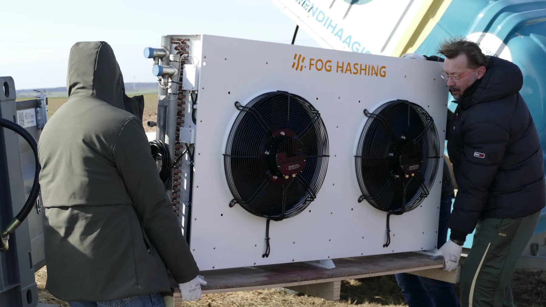 Technicians installing a heat exchanger at a wind-energy mining site in Lithuania